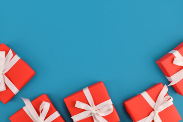 Wall Mural - Small red gift boxes with white ribbons at bottom of blue background with empty copy space