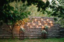 Wooden Wall Decorated Garland With Luminous Bulbs And Electric Lamps Decorated Flowers. Original Wedding Floral Decoration.  Wedding. Reception. Lounge Zone.