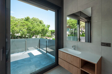 Modern bathroom with large window with modern washbasin.