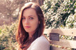 © michnik101 - Portrait of young woman sitting on park bench in soft sunlight
