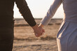 © mavrik - man and woman hold hands on the beach in the rays of the sunset. Photo toned with grain effect.