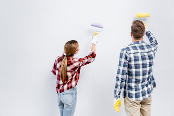 Wall Mural - back view of young couple with rollers painting wall at home