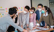 © Greanlnw studio - Group of business office worker team meeting and brainstorm for startup new business. man and woman wearing face mask protective in new normal office preventing coronavirus COVID-19 spreading.