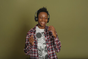 young african american man listening to music with headphones, smiling and dancing on green background