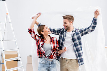 Canvas Print - happy young couple with polyethylene covering at home