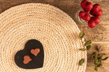 Wall Mural - Top view of a plate with heart-shaped chocolate, jar with shiny hearts on sticks on sisal fabric