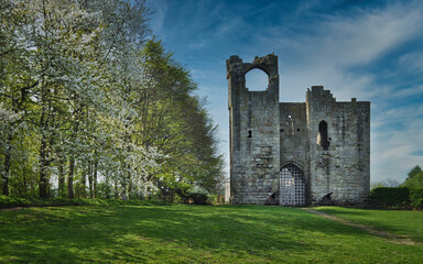 Etal Castle - a ruined medieval fortification in the village of Etal, Northumberland, England. Spring warm day with the blue cloudy sky in the background.