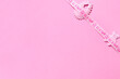Marco babero con cinta color rosa para celebrar nacimiento bebé niña. Fondo rosa. Espacio libre para texto o fotografía del bebé.