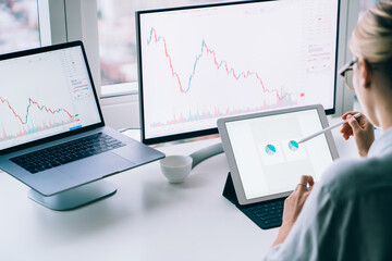 Fototapete - Crop female broker analyzing charts on tablet in office
