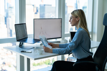 Fototapete - Positive businesswoman working on laptop and computer monitor in office