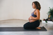 Young pregnant woman trains with yoga in the gym waiting for the birth of her baby - Concept of health and wellness