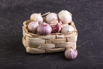 Heads of garlic in a wicker basket on a dark background