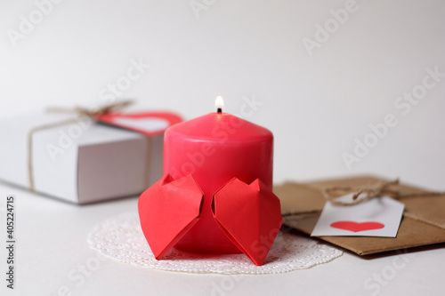 Couple of 3D red paper hearts, burning pink candle on white openwork paper napkin, gifts with labels, hearts closeup view selective focus. Love, Valentine's, women's day, relations, romantic concept 