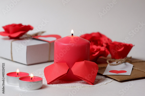 Couple of 3D red paper hearts, burning pink candles on white openwork paper napkin, gifts with labels, hearts, roses closeup view selective focus. Love, Valentine's, women's day, romantic concept 
