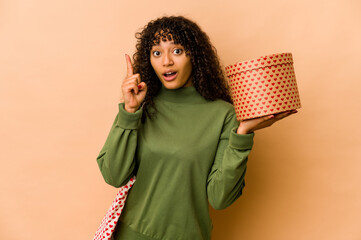 Wall Mural - Young african american afro woman holding a valentines day gift having an idea, inspiration concept.