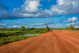 Fototapeta Desenie - Sunset view of a typical red soils unpaved rough countryside road in Guinea, West Africa.