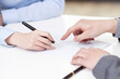 © eastfenceimage - Businesswoman signing document businessman pointing at desk in office