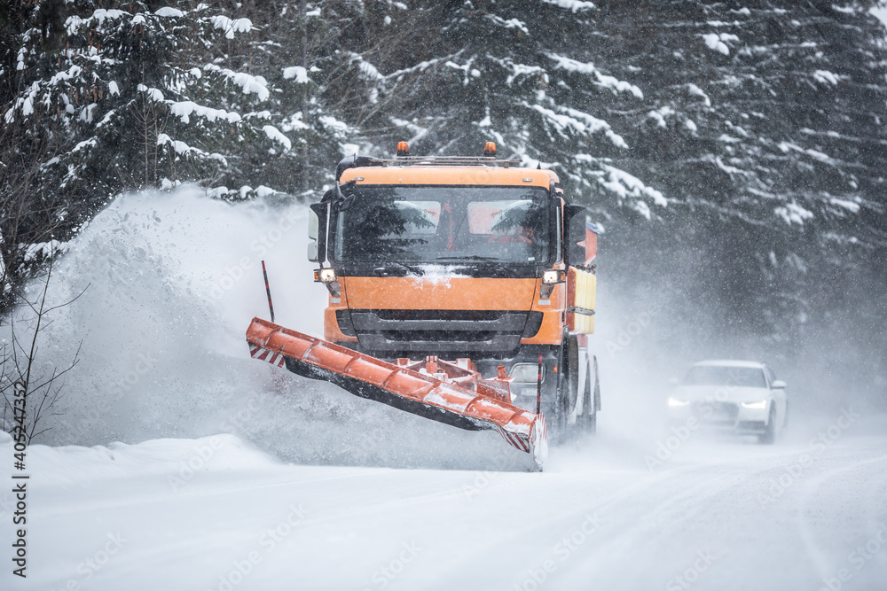 Snowplow clearing road from snow in the forest with traffic lining up behind the truck - obrazy, fototapety, plakaty 