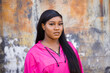 © Ursula Page - Beautiful and serious African American teenage girl with long hair and a pink magenta jacket standing  outside in an urban city setting