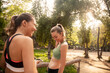 © LOUIS CHRISTIAN/Westend61 - Smiling sportswoman holding mobile phone while talking with friend standing outdoors
