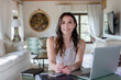 © Emma Innocenti/Westend61 - Smiling female event planner sitting by laptop at home
