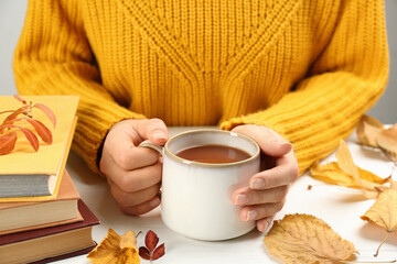 Sticker - Woman with cup of hot drink at white wooden table, closeup. Cozy autumn atmosphere