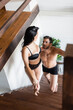© LIGHTFIELD STUDIOS - passionate woman in black lingerie looking at sexy shirtless man while walking upstairs, blurred foreground