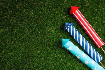 Firework rockets on green grass, flat lay. Space for text