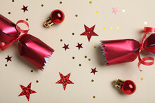 Open Red Christmas Cracker And Decorations With Shiny Confetti On Beige Background, Flat Lay