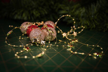 Golden And Red Christmas Baubles With Golden Chain With Stars In Front Of Fir Branch On Green And Golden Background