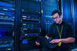 © Erik Isakson - Employee looking at laptop next to server racks