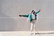 © VITTA GALLERY/Westend61 - Carefree man with headphones and mobile phone dancing with arms outstretched against gray wall