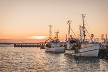 Germany, Schleswig-Holstein, Heikendorf, Fishing Boats Moored In Harbor At Sunset