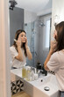 © Mikel Taboada/Westend61 - Woman checking make-up on face while standing in bathroom at home
