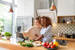 © peter scholl/Westend61 - Smiling female colleagues in office kitchen watching food recipe on tablet