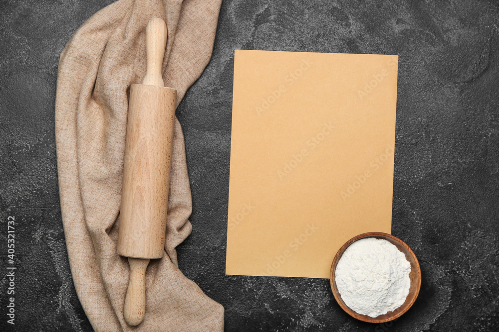 Rolling pin and blank paper sheet on dark background