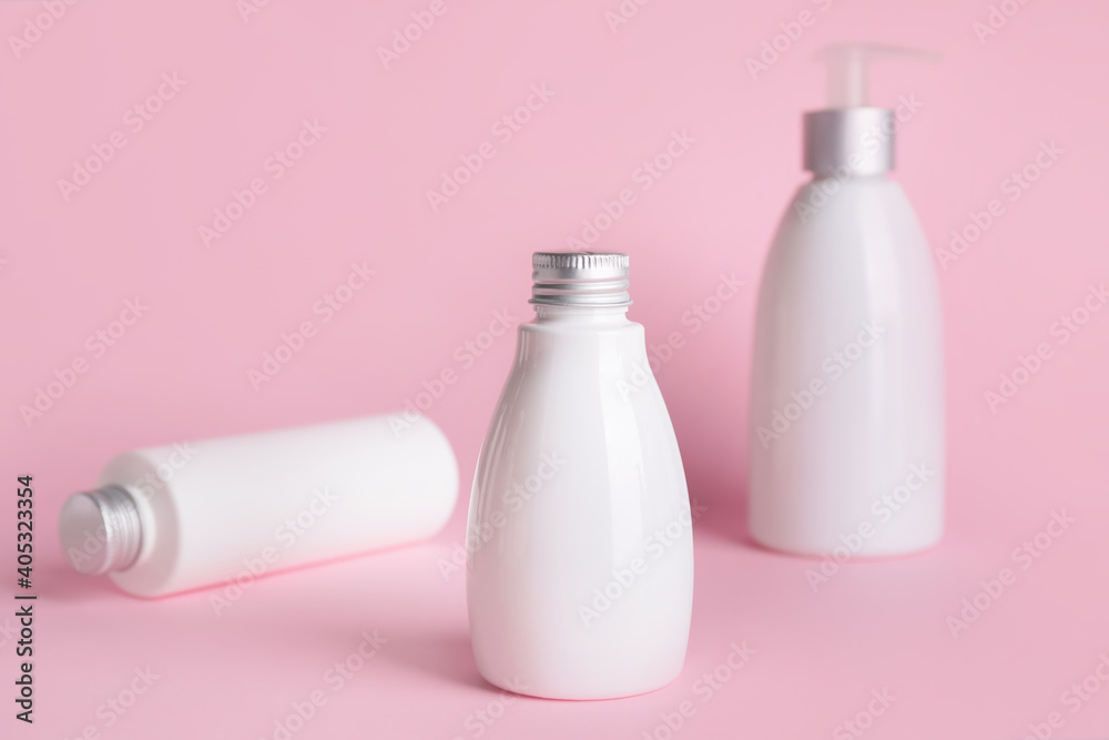 Different bottles of cosmetic products on color background