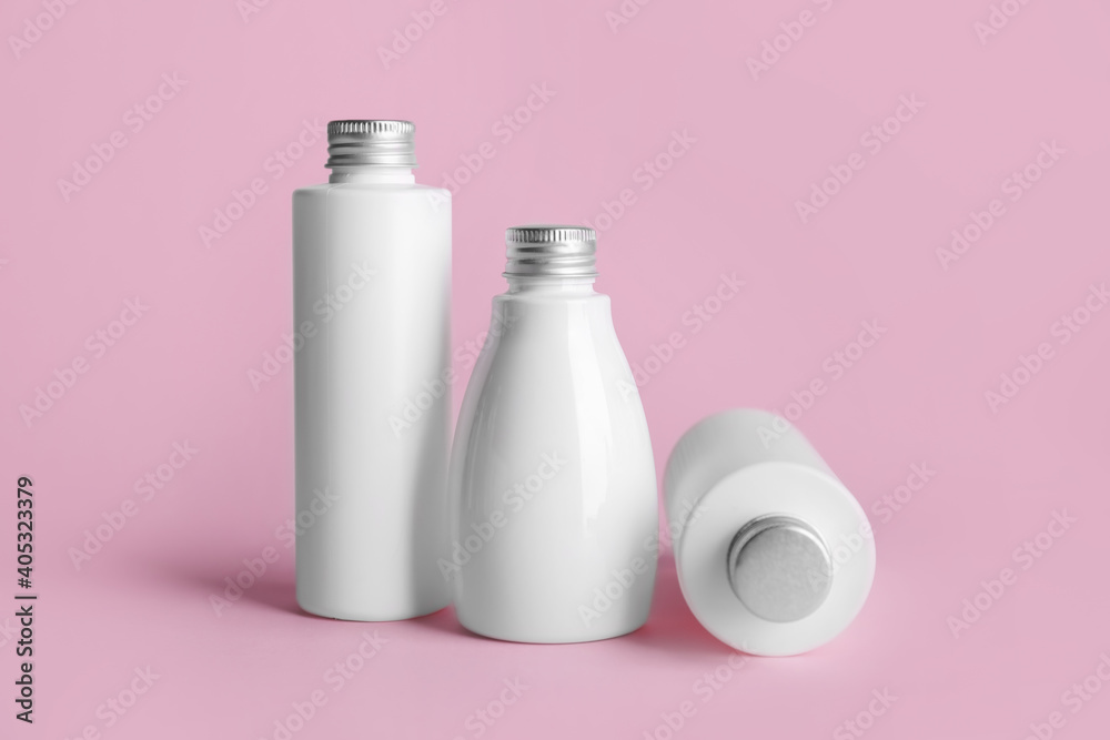 Different bottles of cosmetic products on color background