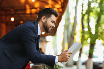 Canvas Print - Young businessman with blank magazine outdoors