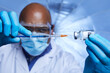 Close up of African American scientist interacting with syringe and glass vial of liquid vaccine in laboratory