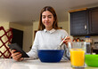 © Leo Cerz - Young woman is learning to cook with her tablet. She is smiling. She is in her kitchen.