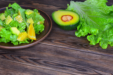 fresh summer homemade salad of vegetables and fruits, orange, lettuce, avocado and sesame seeds, healthy food, organic, vegetarian eco health and immunity products