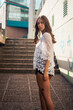 © Mauricio Freytes/Wirestock - A shallow focus of an adult female wearing a white lace shirt with shorts and posing in an alle