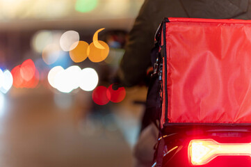 Close up young man working for a food delivery service checking with road motorcycle in the city