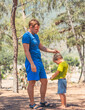 © NOVOZHILOV ANDREI - Happy Childhood fatherhood time photo. Dad son laugh stand in summer forest. Daddy looks with love caress child head. Boy shows t-shirt. Home natural education, fathers day, kid worldview formation