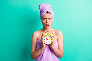 Wall Mural - Photo of unhappy lady hold alarm clock overslept spa salon procedure weekend wear towels isolated teal color background