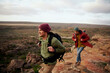 Young male hikers with backpack and winter cap climbing mountain trail