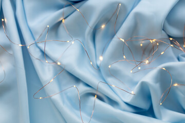 Soft silk cloth or satin fabric texture. Bokeh from lights. Wrinkled fabric pattern. Soft blue color, trends 2021.