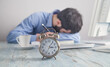 © andranik123 - Tired man in office. Alarm clock on the desk