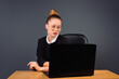 © Viorel - A young business woman with glasses sits at a working computer. Photo on a gray background.